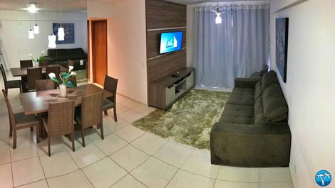 Sala de estar com sofá retrátil, smart tv e varanda. 