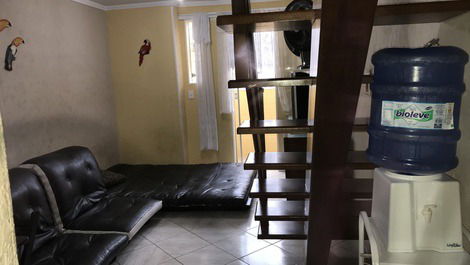 Sala com mesa e um futon de casal e dois de solteiro, ventiladores e  tv smart com acesso Netflix 