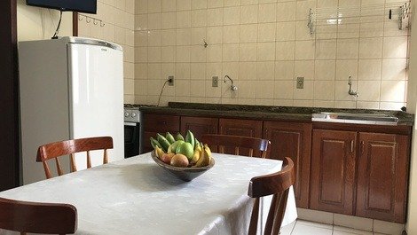 Cozinha do apartamento 202 com fogão 04 bocas e forno, tanque de lavar roupas e varal, mesa, geladeira frost free e Smart TV 