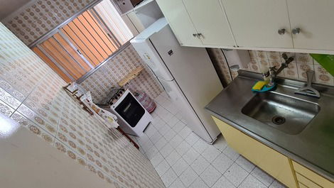 Cozinha com fogão, geladeira, microondas, armários embutidos com utensílios e pia em aço inox