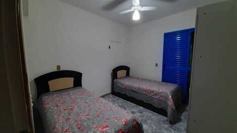 Dormitório social com quatro camas de solteiro , ventilador de teto, armário e terraço.