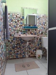 Banheiro também colorido, espaçoso com lavatório de bancada e box. 