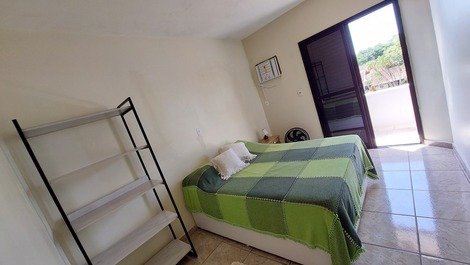 Suíte: cama de casal, armário aberto, ar condicionado, varanda