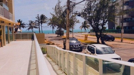 Vista da entrada do prédio, mar e palmeiras