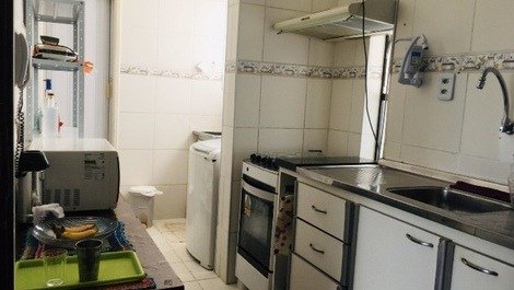 Cozinha mais área de serviço com máquina de lavar e varal . 