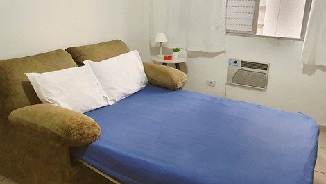 Sala com sofá-cama, ar condicionado, tv, mesa dobrável e cadeira de escritório