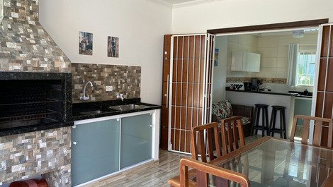 Ambiente integrado churrasqueira, sala e cozinha. churrasqueira completa com grelhas e espetos. 