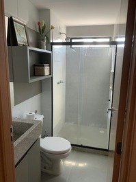 Banheiro amplo com chuveiro a gás e espelho.