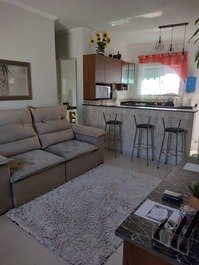 Sala confortável com sofá,tv ,mesa com cadeiras.