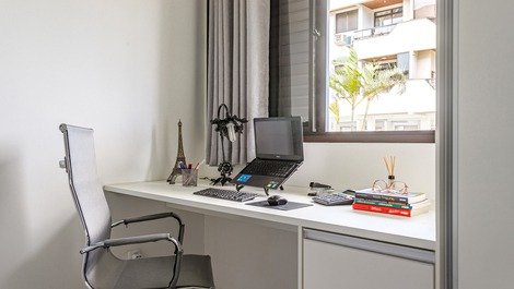 Mesa de escritório com canetas, grampeador e calculadora, com cadeira ergonômica. 