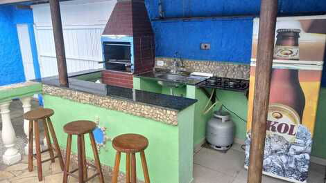 Barzinho da piscina com pia churrasqueira geladeira e cok top 2 mesas 8 cadeiras e 2 guarda sol.