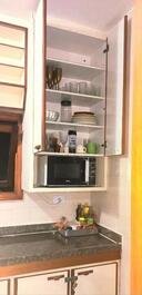 Microondas e cozinha com utensílios 