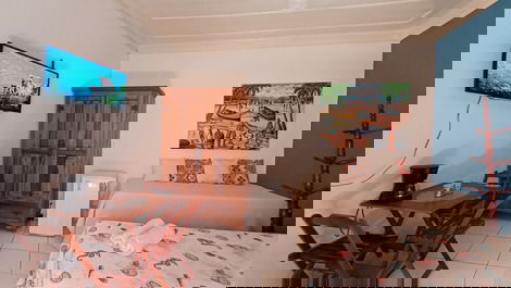 Panorâmica do quarto, incluindo camas, frigobar, armário, tv, mesas, cadeiras e entrada do banheiro