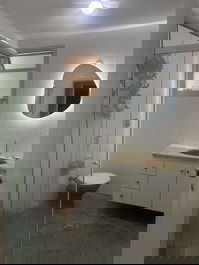 Banheiro da suíte com gabinete e box. 