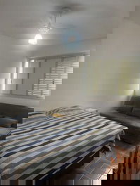 Quarto com cama box e sofá cama e ventilador de teto. 