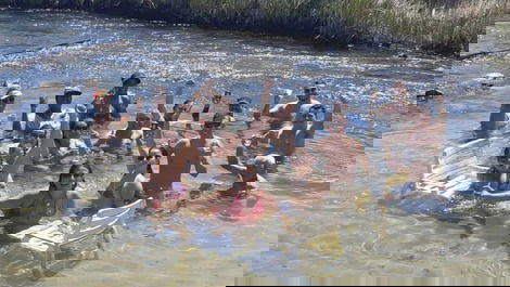 Banho de rio com fundo de areia bem branquinha e águas cristalinas.