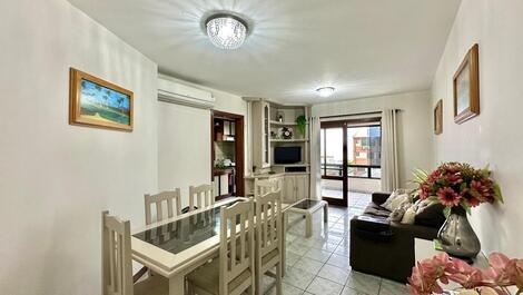 Sala com mesa de jantar de 6 lugares, sofá, televisão e integrada com o espaço da varanda