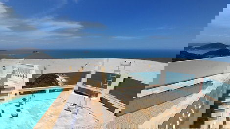 Piscina da cobertura  e área  da churrasqueira, que tem mesas e cadeiras  